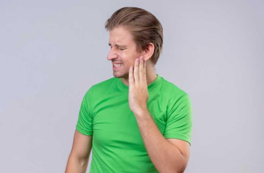 a man in a green shirt is holding his hand to his ear.	